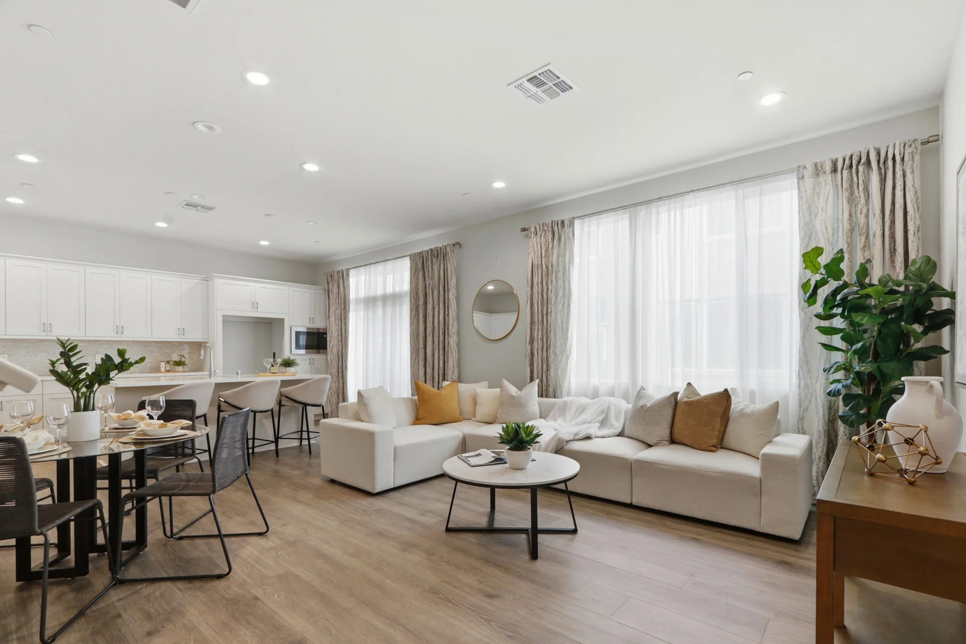 Living area with white sofa and gold pillows, kitchen beyond