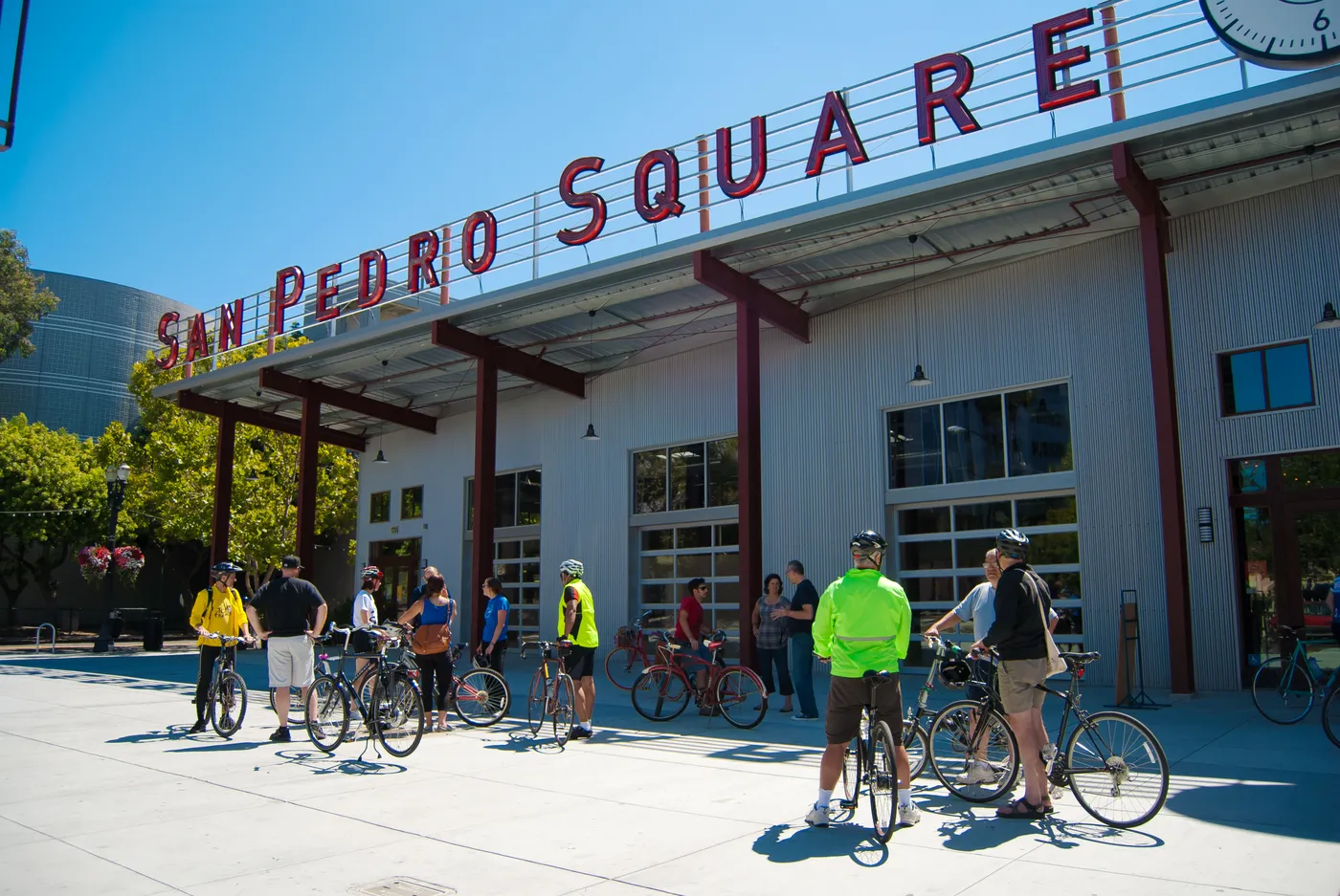 The market hall by day, cyclists gathered under the rooftop letters