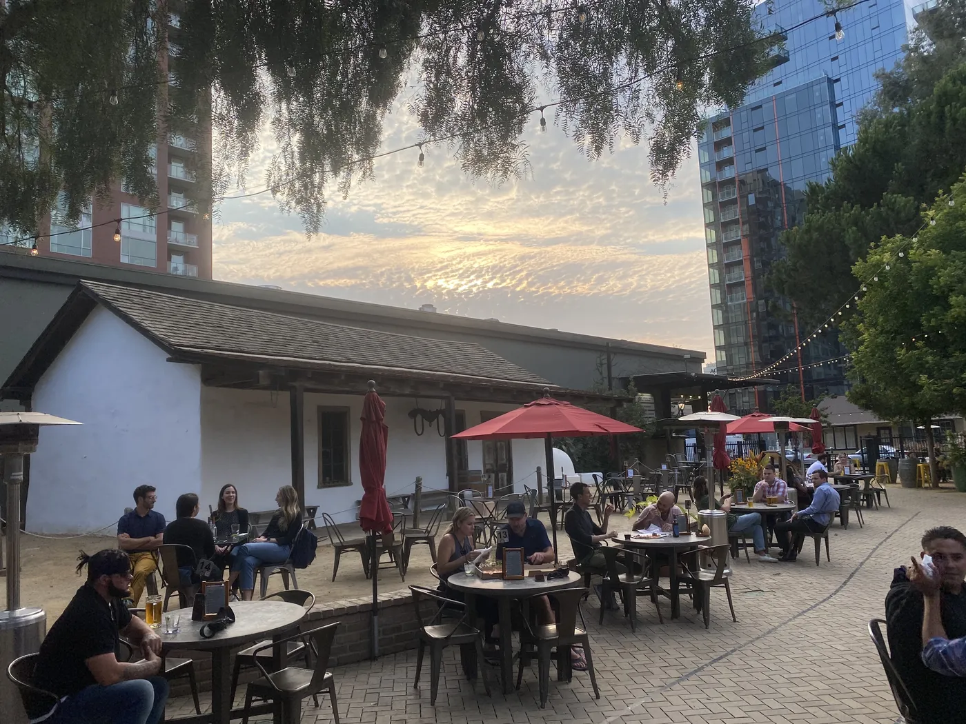 The Square's patio at sunset — diners under umbrellas and string lights, towers behind